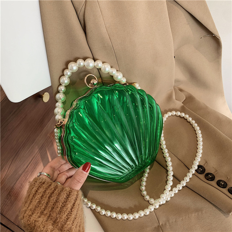 This year's trendy transparent shoulder/crossbody bag with clip handle, featuring a pearl and shell design, is a popular choice among online influencers.
