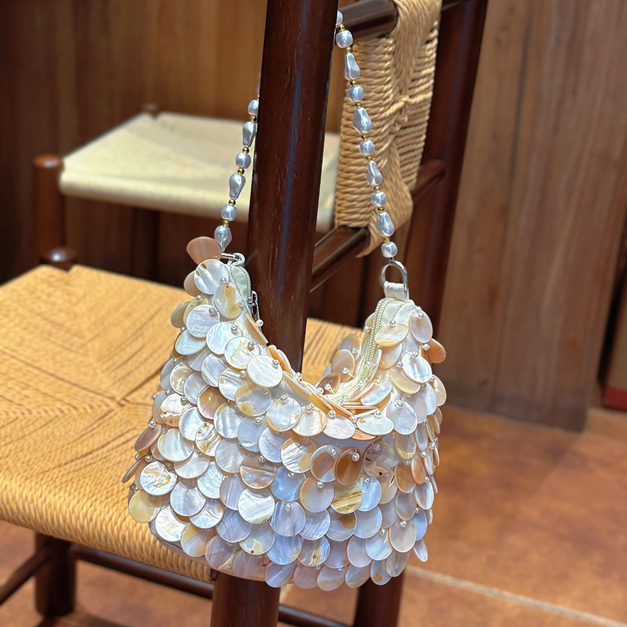Gentle seashell sequined underarm bag with natural mother-of-pearl luster and pearl chain, a vacation-ready bag.