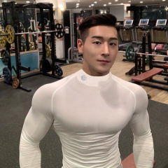 筋肉型の男性のフィットネスは長袖の底のシャツの上着を訓練します。