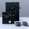 Black gift box with bow, glass, razor, belt, pack