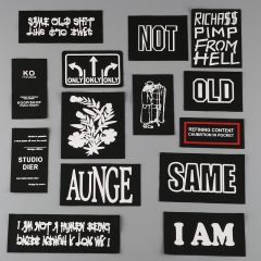 Factory-marketed lettered garment accessories: clothing, bags, shoes, and hats—black-and-white twill fabric with starched labels.