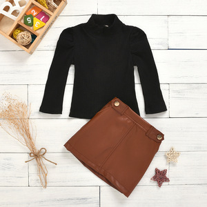 Two piece girl’s dress with high collar and long sleeve top and button open bag leather skirt