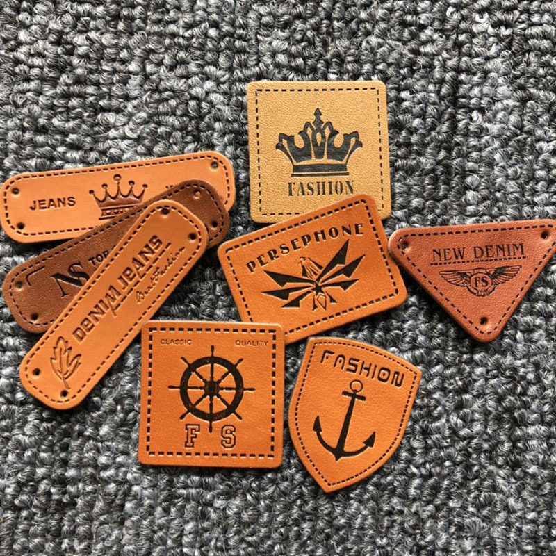 Los fabricantes suministran ropa para hombres y mujeres en stock Logotipo de cuero de PU Logotipo de cuero que hace accesorios de ropa sombrero etiqueta pequeña