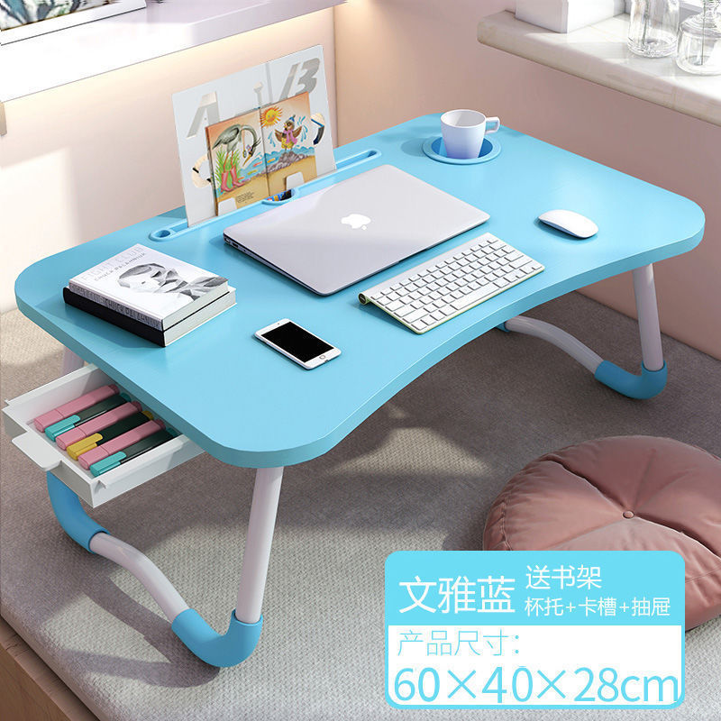 ベッドの上の机の折り畳みの小さい机は引き出しを持っています。|undefined
