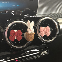 車の香水の香りが可愛いウサギの大根の吹き出し口の少女の心のネットの赤い車の中で飾りを飾って蝶結びをします。