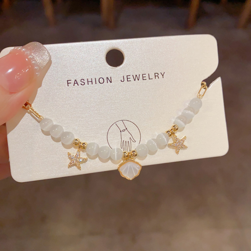 Pulseira leve, luxuosa e elegante com conchas, estrelas-do-mar e pedra olho-de-gato. Transparente, simples e sofisticada._voghion.com