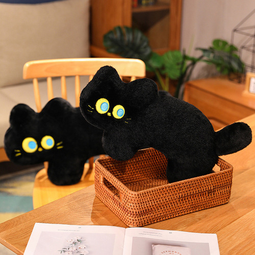Cute black cat pillow in the bedroom for girls to sleep on and play with their mobile phone on the bed with a long pillow on the backrest and a large cushion sofa