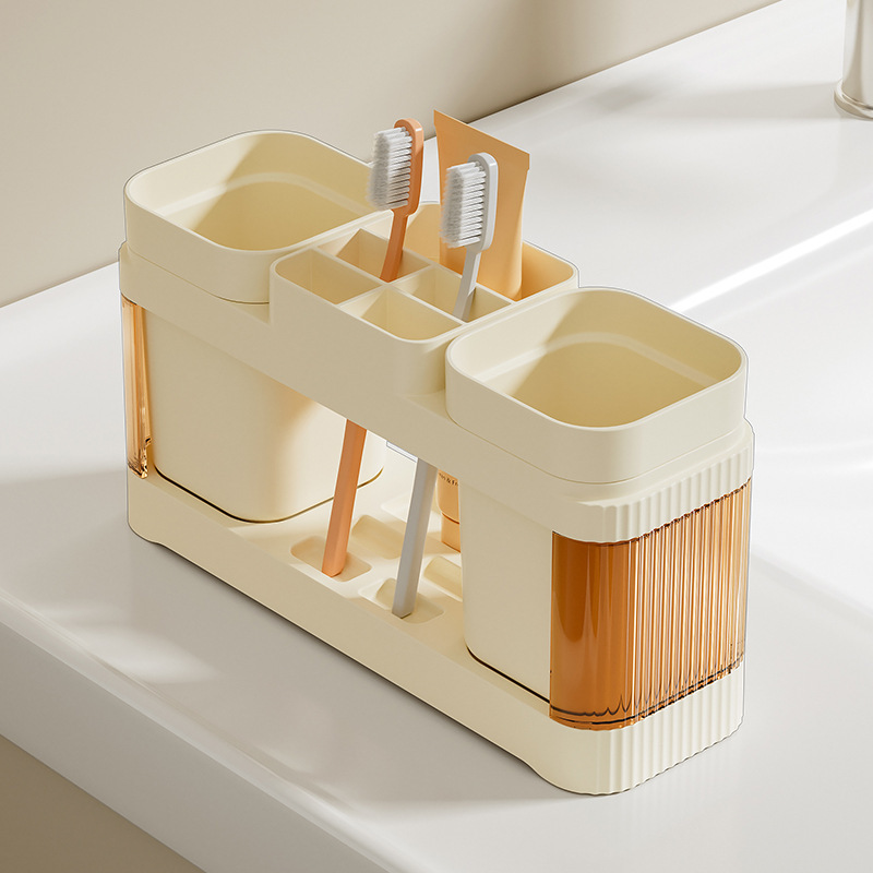 El baño de la Mesa de lavado de la pareja simple contiene un estante de taza de cepillo de dientes, un estante de taza de enjuague bucal de plástico, un estante de mesa de pasta de dientes.