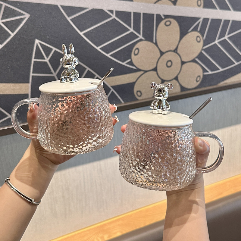 かわいい熊のガラスのコップの女子学生のマグカップは蓋のスプーンの氷河の杯のハンマーの紋様の牛乳の杯を持ってスプーンの取っ手を持ちます。|undefined