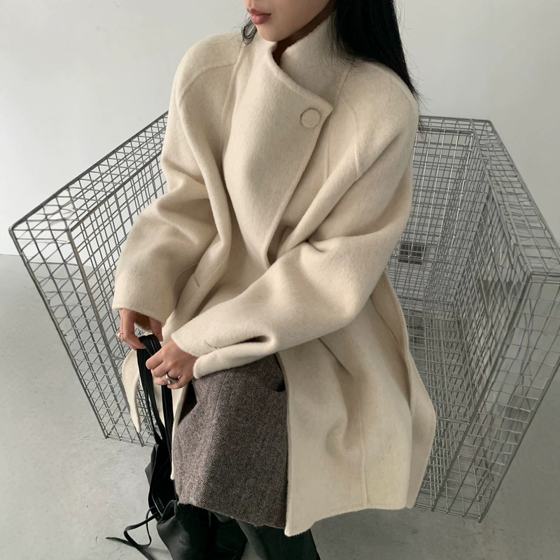 A single-button, mandarin-collar wool coat with a belted waist, a stand-up collar, and a double-faced wool fabric, in a mid-length style