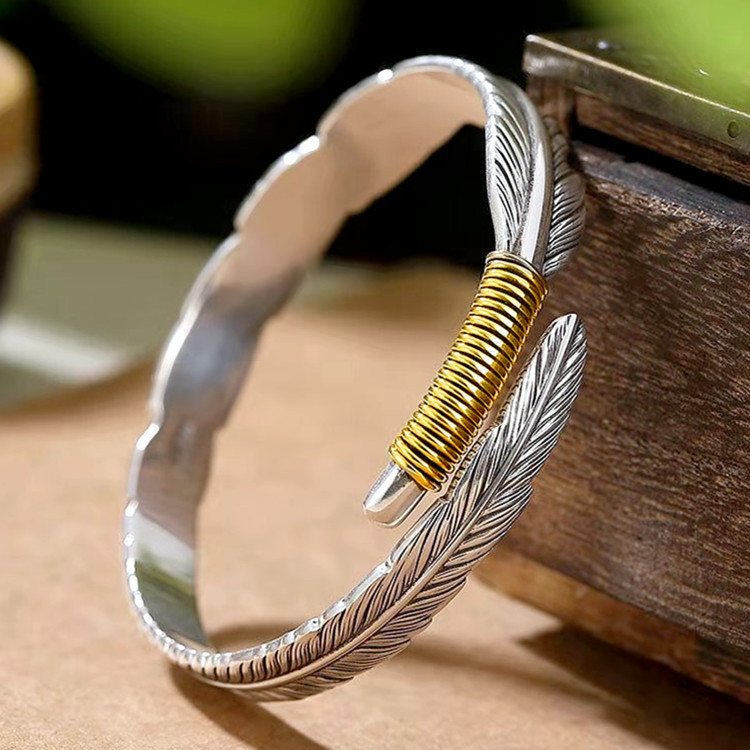 Schlichtes Armband mit alten Federn im Ethno-Stil mit Öffnung. Modetrend für Männer und Frauen mit Blatt-Armband im gleichen Stil_voghion.com