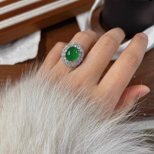 A natural light green jadeite egg face ring with a large, eye-catching green emerald, resembling jadeite, for women.