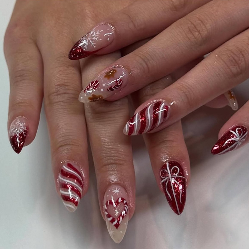 Medium almond-shaped Christmas manicure with glitter pink French nails, heart, snowflake, scepter, and gingerbread man fake nails