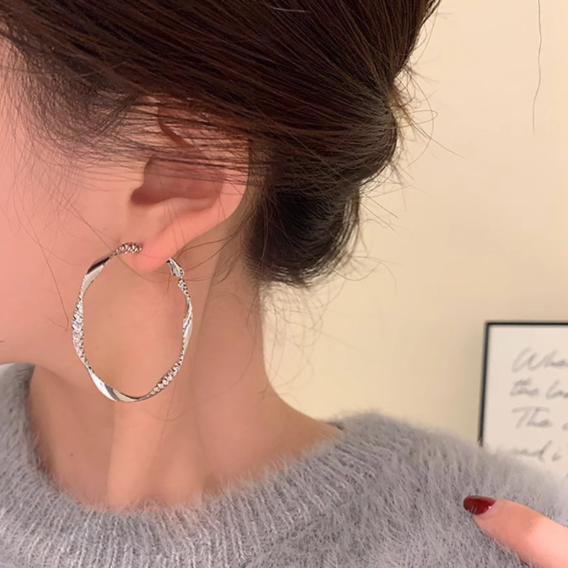 Minimalist and unique design with twisted irregular hoops, metallic cool-toned texture, circular hoop earrings