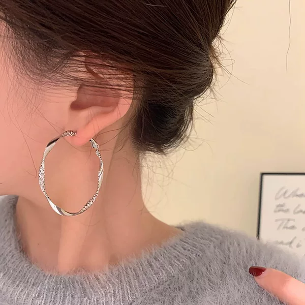 Minimalist and unique design with twisted irregular hoops, metallic cool-toned texture, circular hoop earrings
