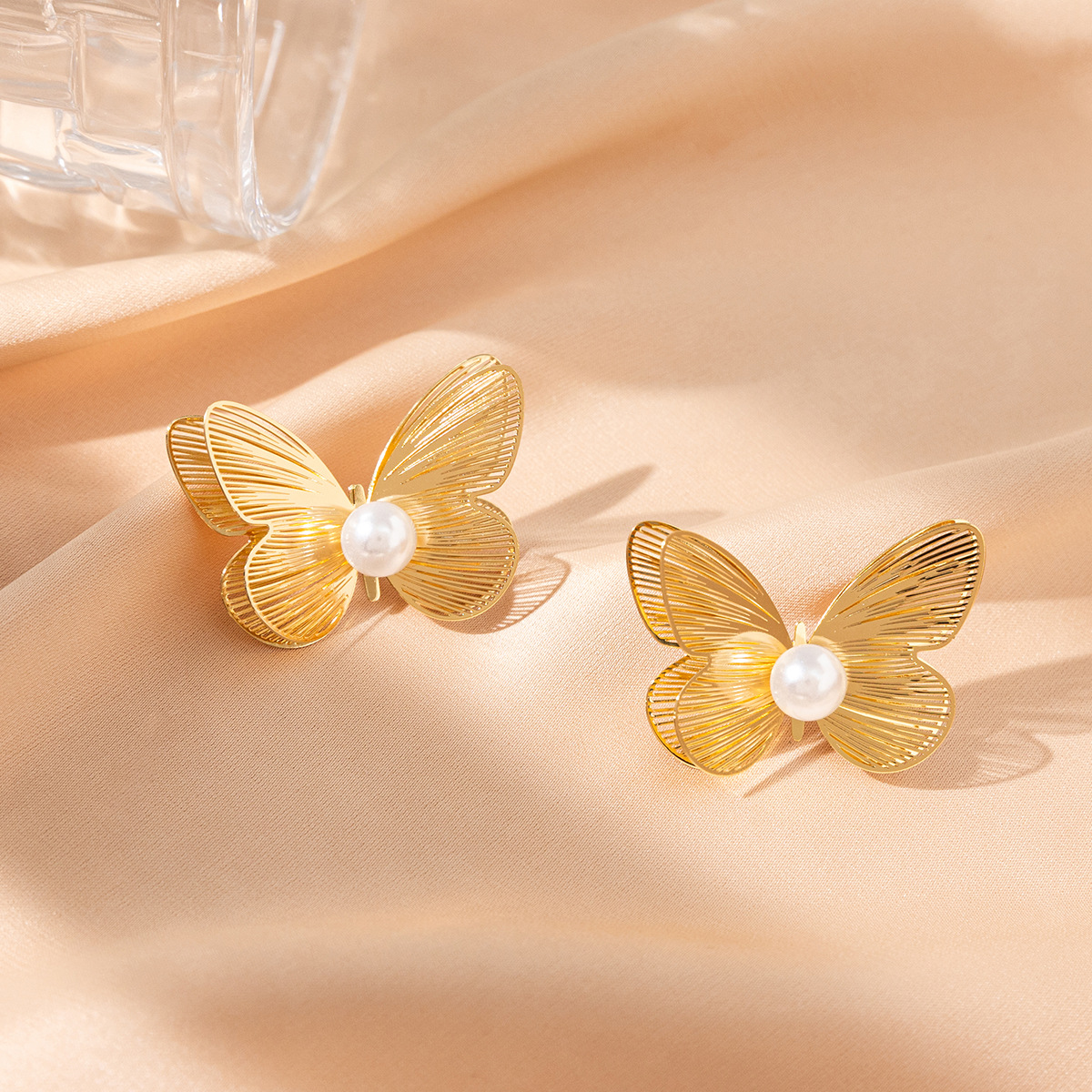 Pendientes de mariposa huecos dorados de alta gama Pendientes de perlas de diseño de nicho de estilo ins femenino Pendientes exagerados al por mayor