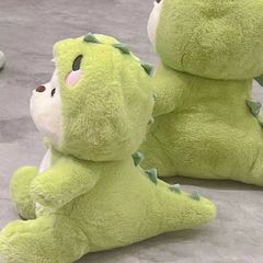 かわいい恐竜の熊のぬいぐるみのぬいぐるみの人形のベッドの上で枕を抱いて誕生日プレゼントの女性