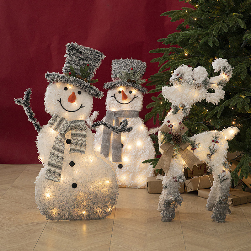 Decoraciones navideñas de muñecos de nieve, adornos de escaparate con una escena de renos de peluche blancos brillantes para la Nochebuena.