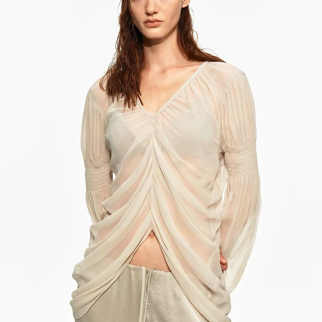 V-neck, flowing, pleated chiffon blouse with slits; subtly sheer; French-inspired, effortlessly chic look with gathered puff sleeves.