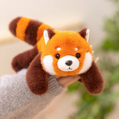 腹ばいになっているパンダのアライグマの人形の人形の手のひらの中の赤ちゃんのぬいぐるみのテーブルは寝て枕の人形の誕生日プレゼントを抱きます。
