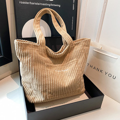卸売りのリュックサックの女性はカジュアルなコーデュロイを合わせて大容量のトートバッグを持っています。