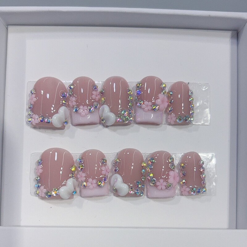 Wholesale of French-style, three-dimensional, small floral white nail tips with rhinestone embellishments, in a nude pink base, for a pure and innocent, girly look