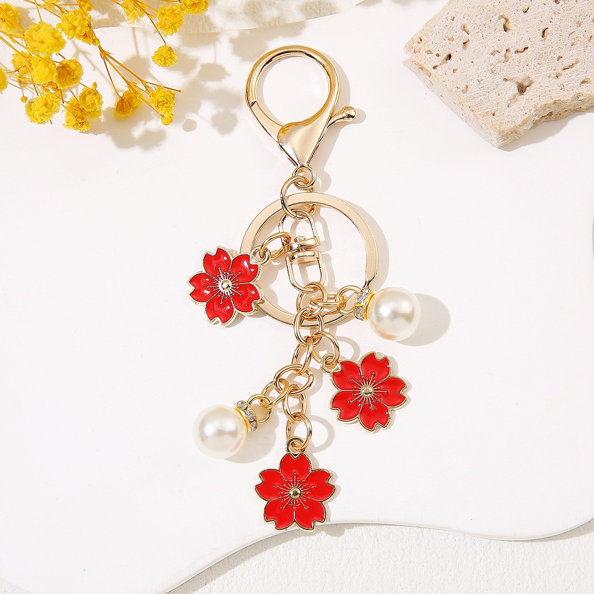 Venta al por mayor de llaveros de flores de cerezo japoneses que caen a mano, adornos de bolsos de mujer que gotean aceite, colgantes de perlas para parejas de novias