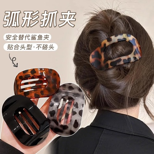 Shellfish-shaped hair clip with a round, flat back, designed to clip onto a woman's full, rounded hair bun, featuring an arched tail hair clip as a head accessory.