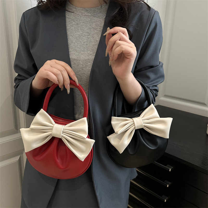 2025 primavera y verano nuevo nicho de diseño de arco bolsos portátiles de mujer alta sensación pequeña bolsa redonda roja