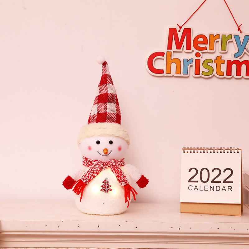 クリスマス発光雪だるま人形のデスクトップに子供の祝日のプレゼントを飾っています。|undefined