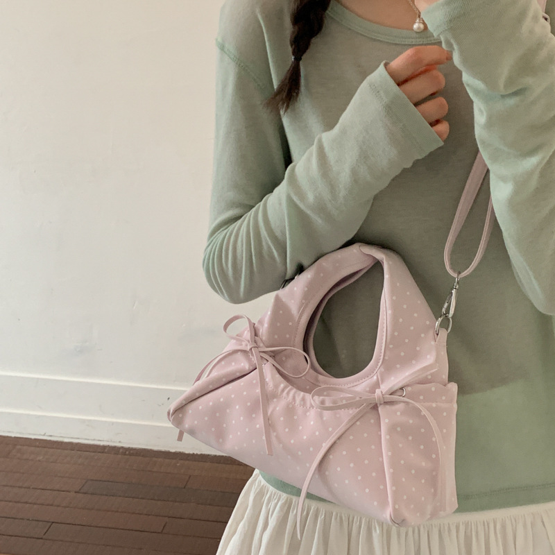 Bolsa de mano de arco exquisita coreana para mujeres verano 2026 simple diaria versátil onda punto sensación de hombro mochila