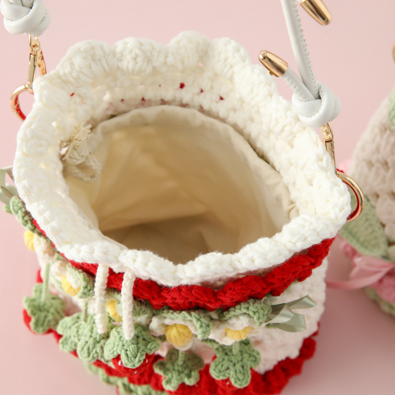 ネットの赤いタイプの編み物の手作りのスカーフのバケツの包みのセットのイチゴのケーキのすずらんの花束の包みはイチゴのバケツを抱いています。|undefined