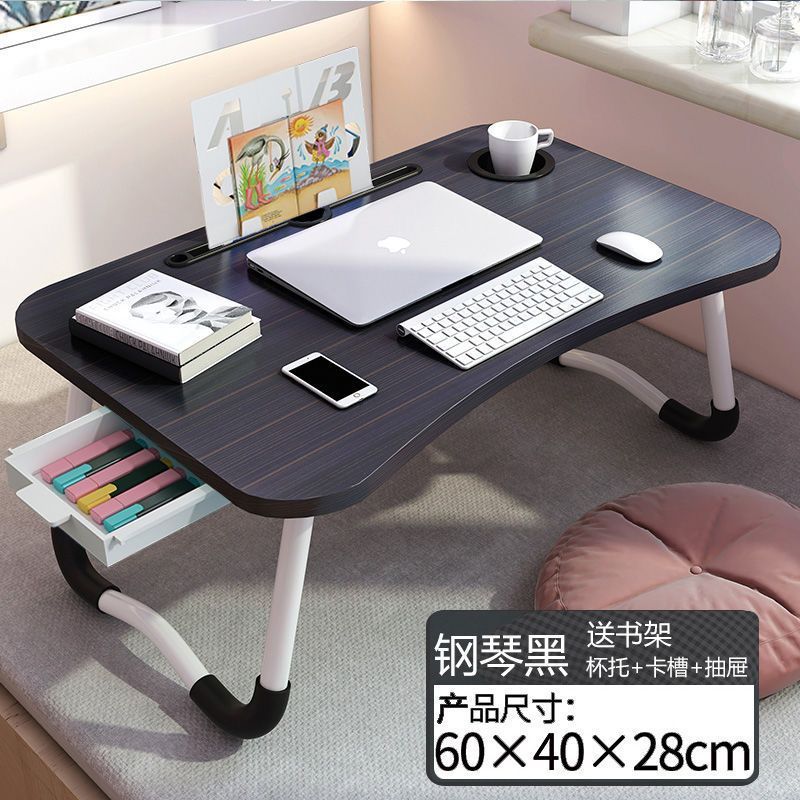 ベッドの上の机の折り畳みの小さい机は引き出しを持っています。|undefined