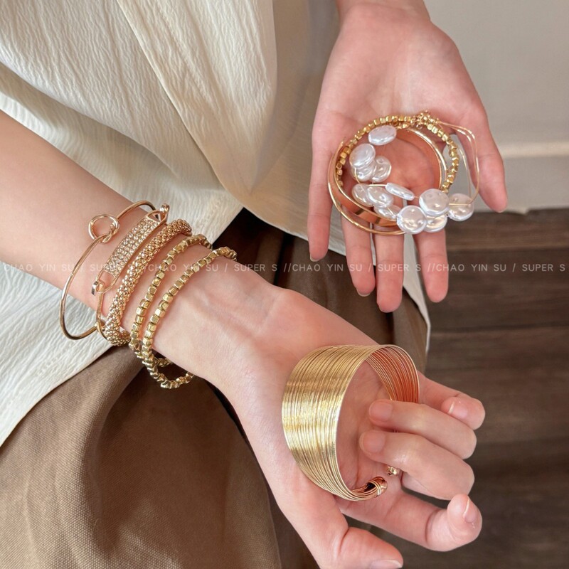A Set of Bracelets That Are Both Fashionable and Versatile, Featuring Wide Edges, Multi-Layered Design, and a Gold-Colored Vacation Style, Perfect for Spring and Summer