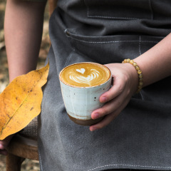 手作りのレトロな手でコーヒーカップを握って、日本式の厚い粗陶磁ラテコーヒーカブマグカップ250mlを引っ張る