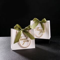 新しい白い喜糖箱は結婚して緑のリボンの喜糖袋を持っています。