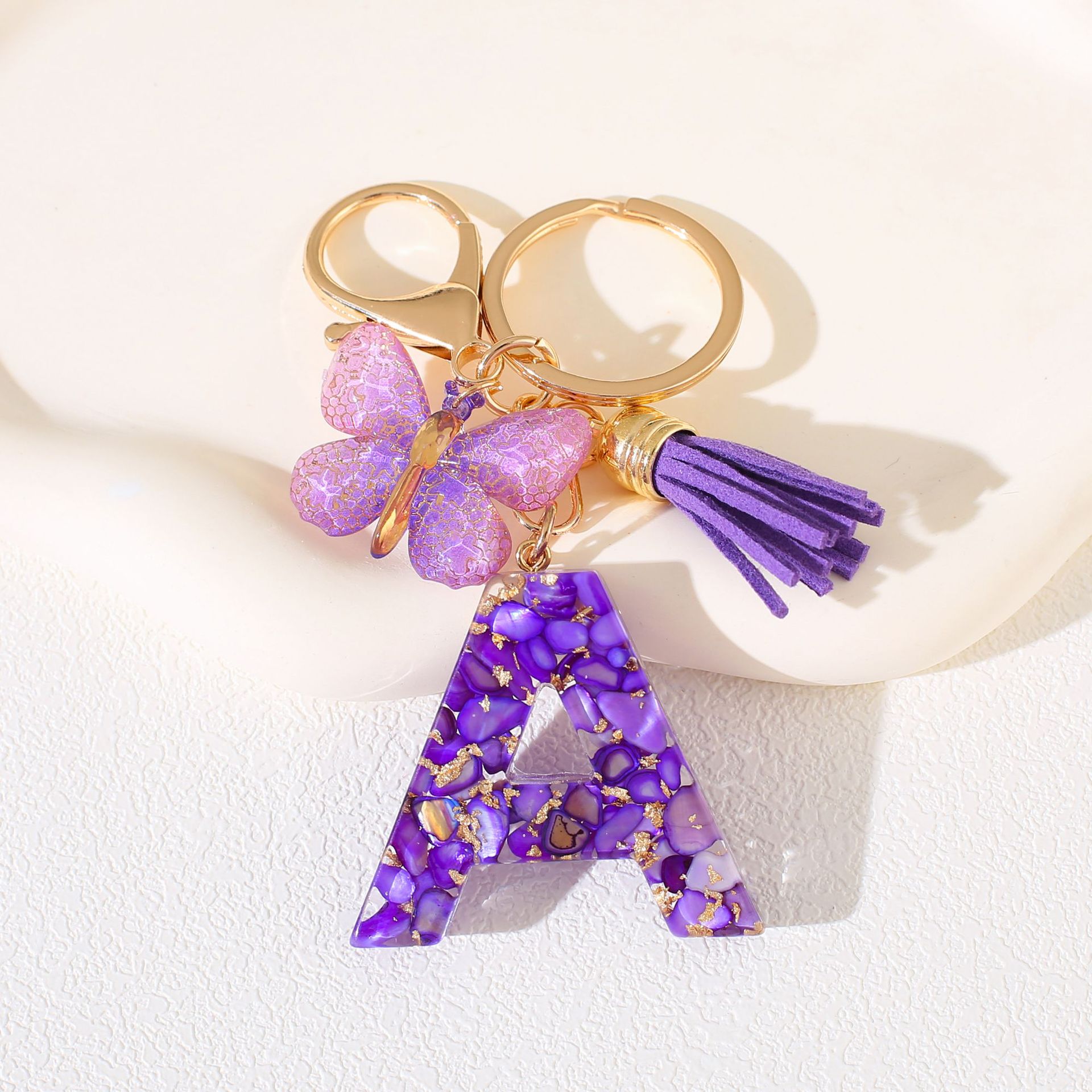 Fábrica directa de Yiwu accesorios de resina de goteo de embalaje llavero anillo de metal letras mariposa brilla colgante damas