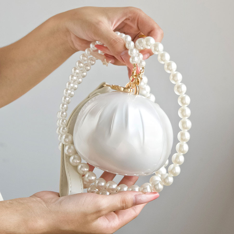 French-style, delicate, and rounded evening clutch with pearl shoulder straps, offering a subtle sheen and a luxurious feel, perfect for wedding dresses