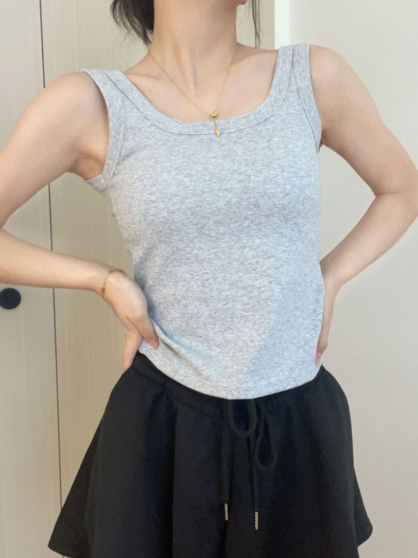 純色のベストのストラップの女性は胸のクッションを持っています。|undefined
