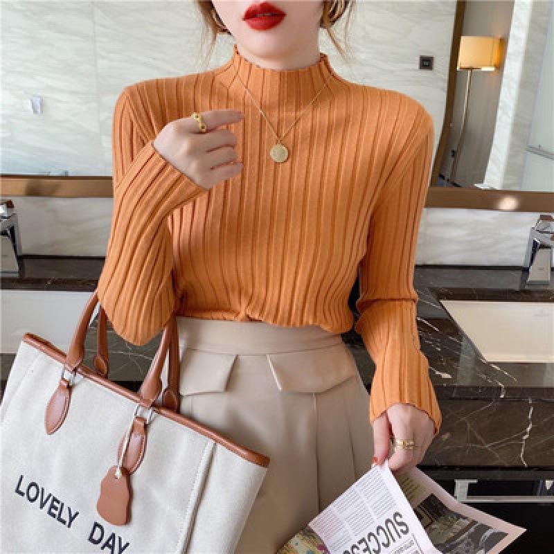 坑条半高襟のカーディガンの中にセーターを着ています。