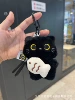 Black cat holds fish keychain and squeaks