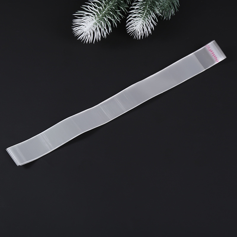 Transparent self-adhesive plastic pouch with a slim, elongated shape, suitable for packaging items such as pens, toothpicks, straws, brushes, knives, forks, and spoons.