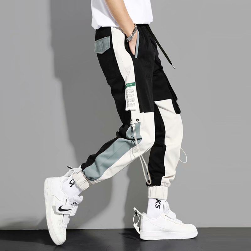 工装ズボンの男性青少年は足を組んで学生の潮のヒップホップの潮の札をつなぎ合わせます。