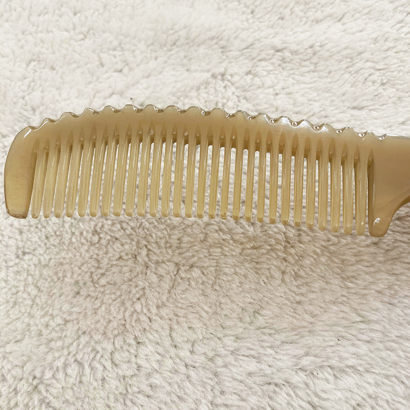 ショートヘアの長い柄の男性の髪を櫛にして、牛の角の櫛を整えます。|undefined