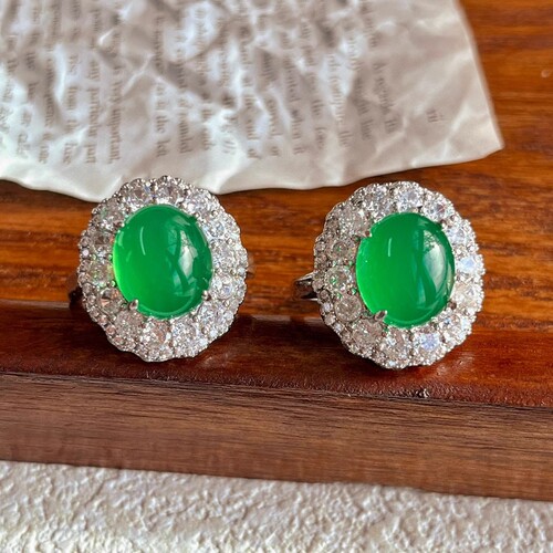A natural light green jadeite egg face ring with a large, eye-catching green emerald, resembling jadeite, for women.
