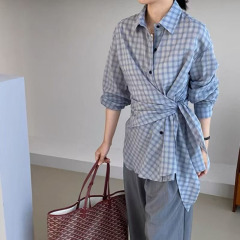 韓国系は青い格子の長袖のシャツを着ています。