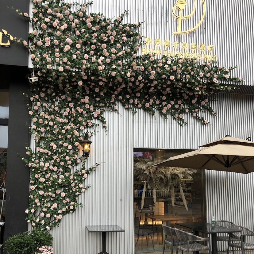 Decorative scene pipeline entwined with vines and fake flowers arches, covering the background wall of a simulated rose vine gate header