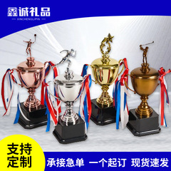 金属のトロフィーを持っています。バスケットボールのサッカー試合の学生試合です。金銀の銅のトロフィーは字を彫って金色を印刷します。