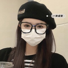 ベレー帽の女性は日本のシンプルなアルファベットの金属標識をつけて保温します。