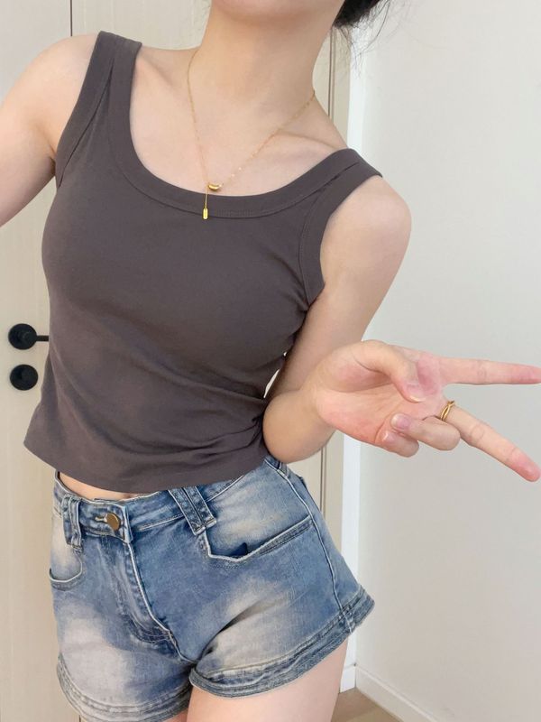 純色のベストのストラップの女性は胸のクッションを持っています。|undefined